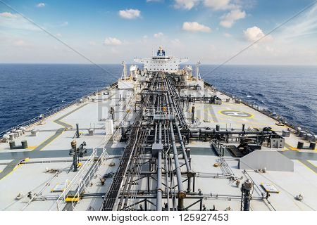 Deck of oil tanker in the blue ocean under sky - view from foremast.