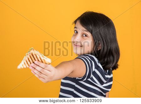 indian girl eating sandwich, asian girl and sandwich, cute indian girl posing with sandwich on yellow background