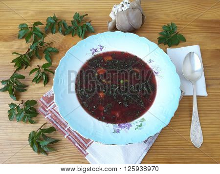 Red beet soup with goutweed and Oyster mushrooms in plate, on table