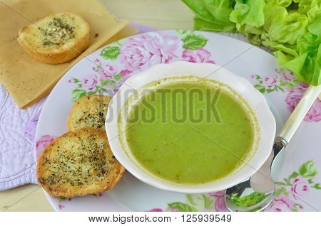 Bowl with fresh green pea soup (pottage) with pieces of garlic bread