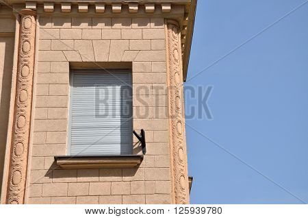 Window covered with sunblind on a renovated building facade and blue sky