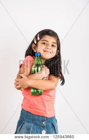 indian girl opening cold drink bottle, asian girl drinking cold drink in pet bottle, girl kid and cold drink, indian cute girl with lemon or carbonated cold drink in plastic bottle, isolated on blue