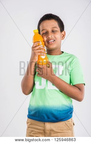 indian boy with cold drink bottle, asian boy holding cold drink bottle, small boy and cold drink, indian cute boy drinking mango juice or orange juice in plastic bottle