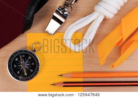 Orderliness White Scout Rope, Scarf, Whistle, Compass, Pencil And Paper Note On Wooden Table.