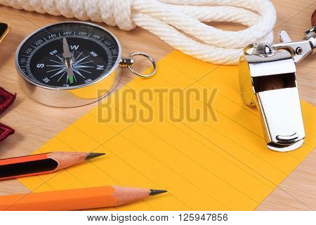 Orderliness White Scout Rope, Whistle, Compass, Pencil And Paper Note On Wooden Table.