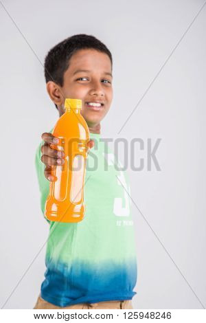 indian boy with cold drink bottle, asian boy holding cold drink bottle, small boy and cold drink, indian cute boy drinking mango juice or orange juice in plastic bottle