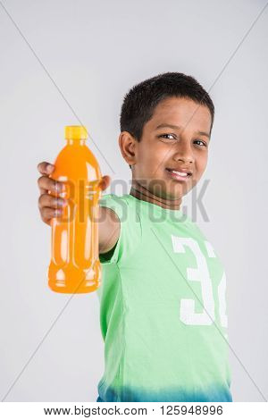 indian boy with cold drink bottle, asian boy holding cold drink bottle, small boy and cold drink, indian cute boy drinking mango juice or orange juice in plastic bottle