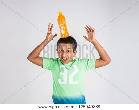indian boy with cold drink bottle, asian boy holding cold drink bottle, small boy and cold drink, indian cute boy drinking mango juice or orange juice in plastic bottle