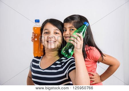 two indian girls with cold drink bottle, two asian girls posing with cold drink in pet bottle, 2 girl kid and cold drink, indian cute girls playing with mango juice or orange juice bottle