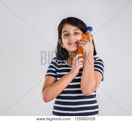 indian girl with cold drink bottle, asian girl drinking cold drink in pet bottle, girl kid and cold drink, indian cute girl drinking mango juice or orange juice in plastic bottle