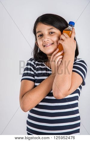indian girl with cold drink bottle, asian girl drinking cold drink in pet bottle, girl kid and cold drink, indian cute girl drinking mango juice or orange juice in plastic bottle