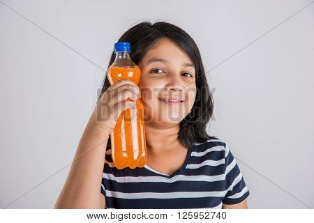 indian girl with cold drink bottle, asian girl drinking cold drink in pet bottle, girl kid and cold drink, indian cute girl drinking mango juice or orange juice in plastic bottle