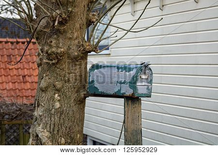 Old mailbox, standing on a beam near the house.