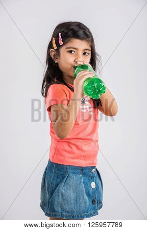 indian girl with cold drink bottle, asian girl drinking cold drink in pet bottle, girl kid and cold drink, indian cute girl with lemon or carbonated cold drink in plastic bottle, isolated on blue