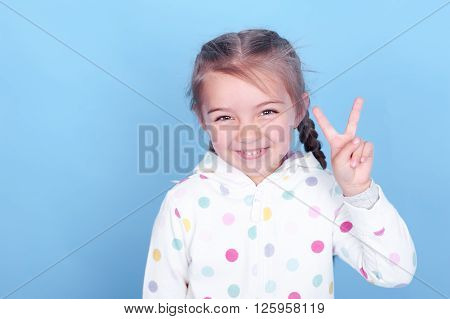 Laughing baby girl 4-5 year old having fun in room over blue. Happiness.