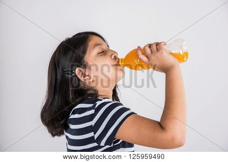 indian girl with cold drink bottle, asian girl drinking cold drink in pet bottle, girl kid and cold drink, indian cute girl drinking mango juice or orange juice in plastic bottle