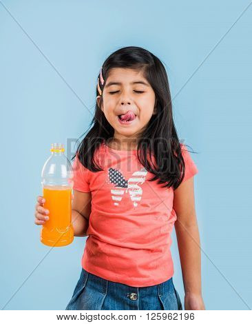 indian girl with cold drink bottle, asian girl drinking cold drink in pet bottle, girl kid and cold drink, indian cute girl with mango or orange cold drink in plastic bottle, isolated on blue