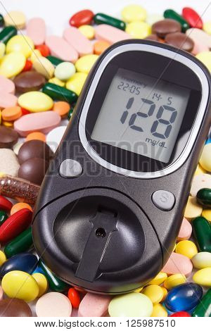 Glucose meter with result of measurement sugar level and heap of colorful medical pills capsules , concept of treatment diabetes and health care