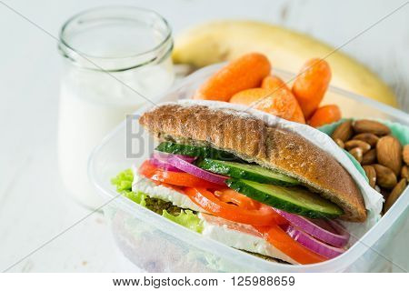 Vegan sandwich in lunch box with carrots and nuts - healthy food to go concept, wood background, copy space