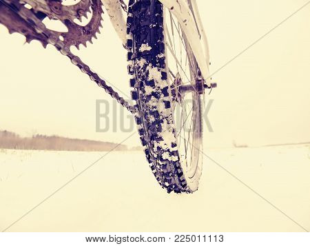 Close-up of the rear wheel of mountain bicycle in snowy meadow in the countryside. Detail of the mountain bike. Extreme sportive backgrounds. Concept of the extreme sport lifestyle.