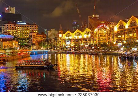 CLARKE QUAY, SINGAPORE - AUGUST 16, 2009: A traditional bumboat on the Singapore River at night, with Clarke Quay on the left and Riverside Point on the right.