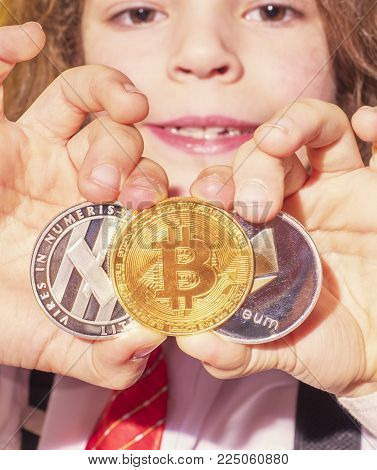 The Caucasian child holds bitcoin BTK , lithecoin LTC , etherum ETH in his hand, select the focus on the gold coin. Gold bitcoins digital virtual money , digital cryptococci