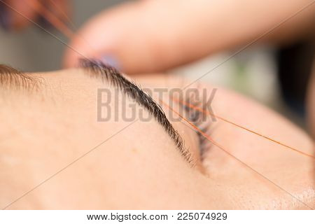 Grooming the eyebrows thread in a beauty salon. close .