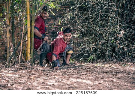 AYUTTHAYA, THAILAND - DECEMBER 17: Ancient swordman be ambush alert near tree prepare for attack with swords on December 17, 2017 in Ayutthaya.
