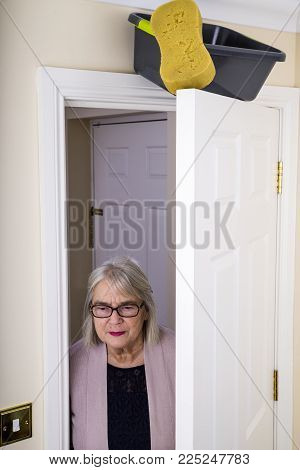 April Fool's Day Trick.
Lady walking into a room, with a bucket of water and sponge about to fall on to her.  April Fool's Day joke.