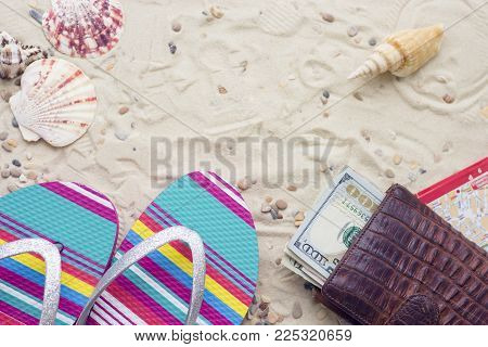 Enjoying vacation mood, beach sneakers and money purse on white sand background. Top view, closeup.