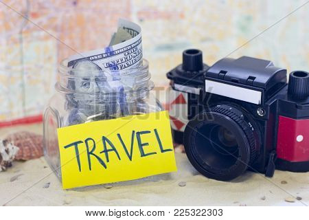 Planning for vacation, saving money for next trip. Vintage camera on sand background