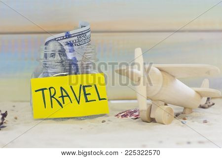 Planning for vacation, saving money for next trip. A toy plane on sand background