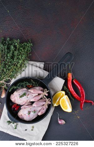 Small raw quals with some spice ready for cooking on black round pan .