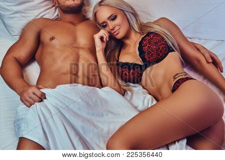 Sexy couple. Portrait of sexy husband and wife, relaxing in bed, honeymoon.