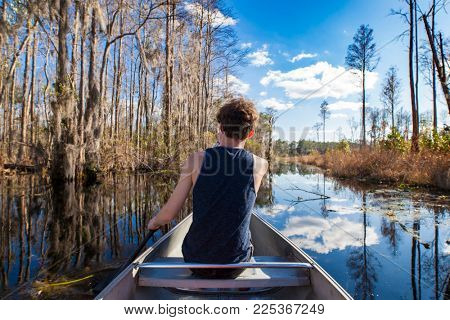 POV shot of canoe with teen paddling in Okefenokee swamp.