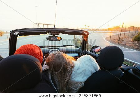 Romantic couple on honeymoon or amazing getaway travel trip in love, ride into sunset horizon on small red convertible cabriolet car with open roof with epic sunset flares, concept relationship goals