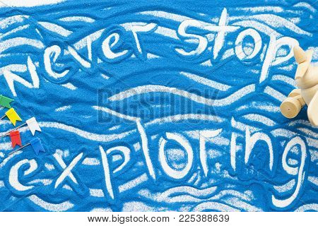 Never Stop Exploring Inscription On A Blue Colored Sand With Waves And Decorations