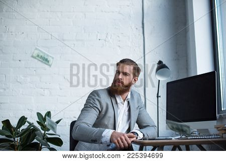 Businessman Sitting At Table And Looking At Falling Dollars