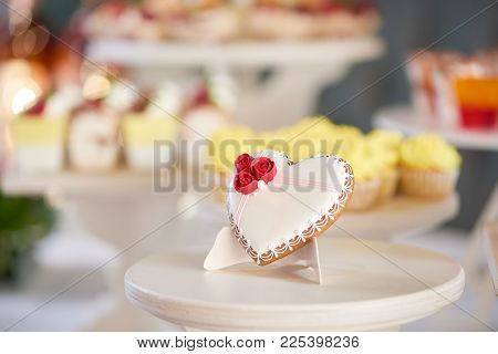 Glazed Gingerbread Heart Stands On The Wooden Stand In The Restaurant. It S Decorated With Glaze Red