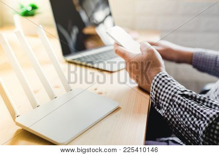 Closeup Of A Wireless Router And A Man Using Smartphone On Living Room At Home Ofiice