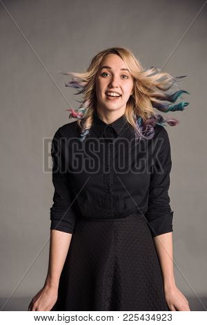 Portrait Of Jumping Young Woman With Colored Hair In Black Shirt Isolated On Gray Studio Background