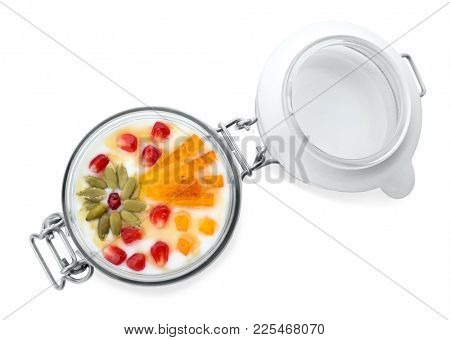 Yogurt with date plum, pomegranate and pumpkin seeds in jar on white background