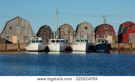Blue fishing boat in front of oysters barns in Malpeque, Prince Edward island also called PEI