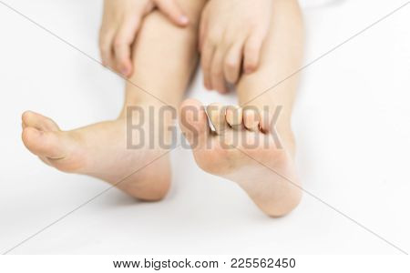 The Hands Of The Little Boy Hold Their Feet On A White Background.