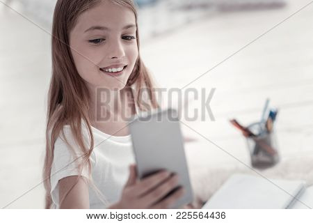 Taking Selfies. Beautiful Vigorous Long-haired Smiling Girl Wearing A White Shirt And Taking Photos 