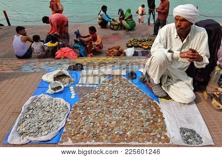 Haridwar, India - November, 6th, 2017. Man Selling Old Coins On The Riverbank Of Ganga River In Hari