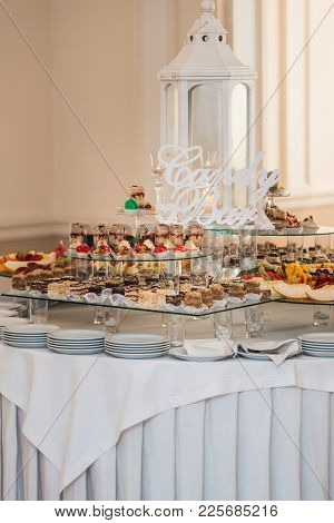 Candybar In A Restaurant. Decorated White Table Fool Of Sweet Pastry. Wedding Sweets