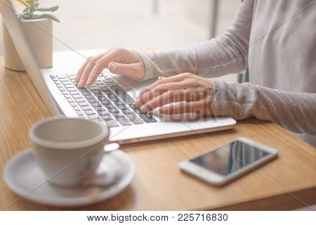 Woman Typing On Laptop Computer And Using Smart Phone