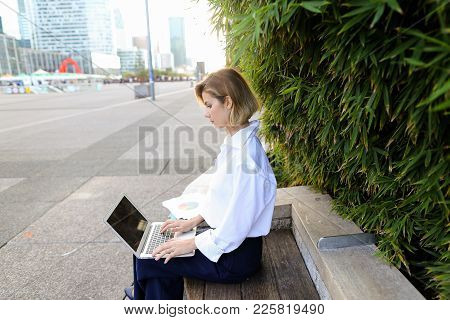 Female Statistician Working With Color Diagrams And Laptop Outdoors Near Green Plant. Concept Of Wor