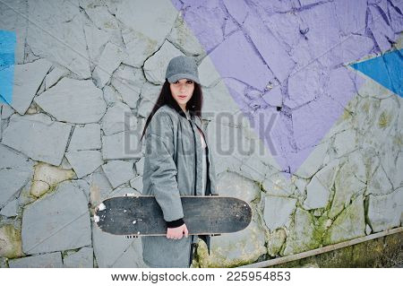 Stylish Brunette Girl In Gray Cap, Casual Street Style With Skate Board On Winter Day Against Colore